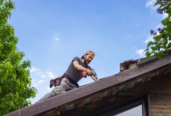 Shows man on rooftop performing repairs