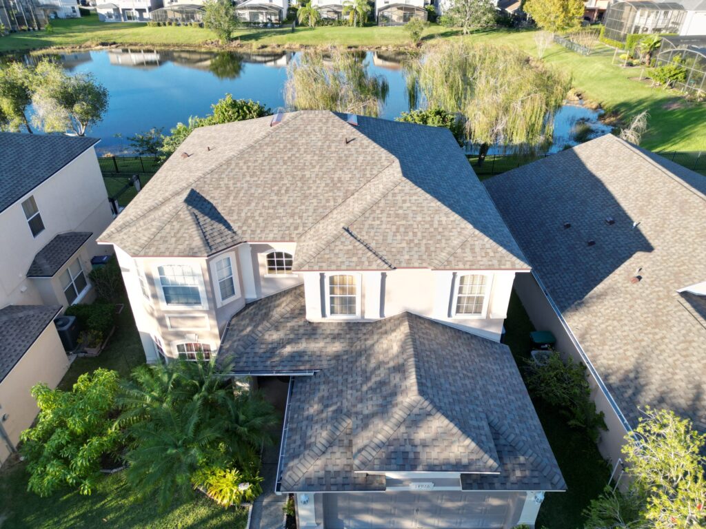 Image shows home in Florida which has a new roof recently installed by Eave & Gable Roofing. The shingles are CertainTeed Weathered Wood colored architectural asphalt shingles.