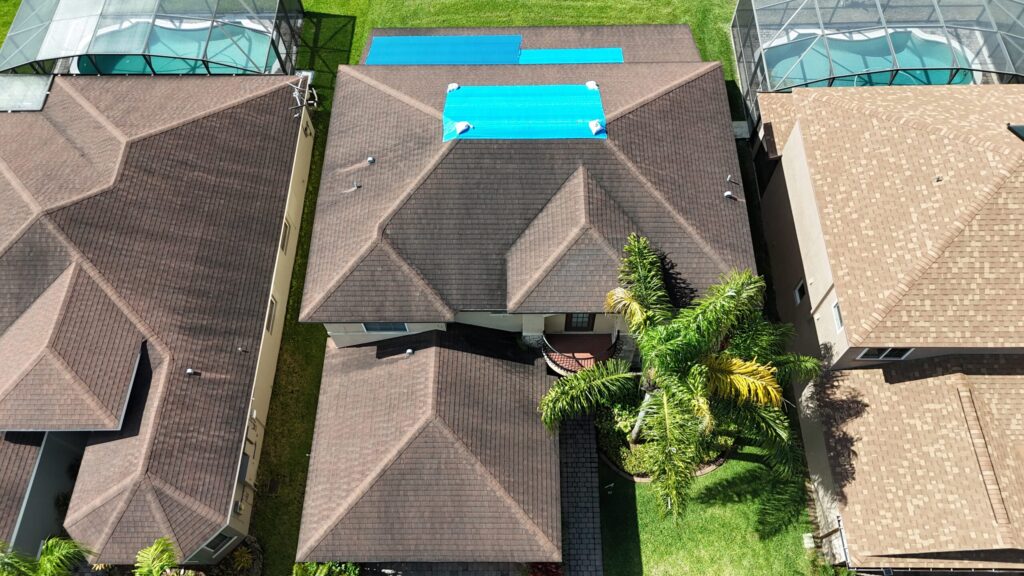 Image shows house in Florida with a blue tarp covering a damaged part of the roof.